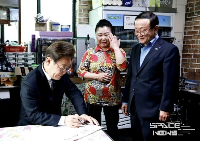 지난 6월 13일, 이재명 대통령이 김덕현 연천군수와 함께 연천군 청산면을 방문해 경기도 농촌기본소득 시범지역 소상공인과 담화를 나누며 방명록을 작성하고 있다.